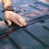 Close-up of hands fitting the GapShield™ Tailgate Gap Cover onto a truck bed, demonstrating the straightforward installation process