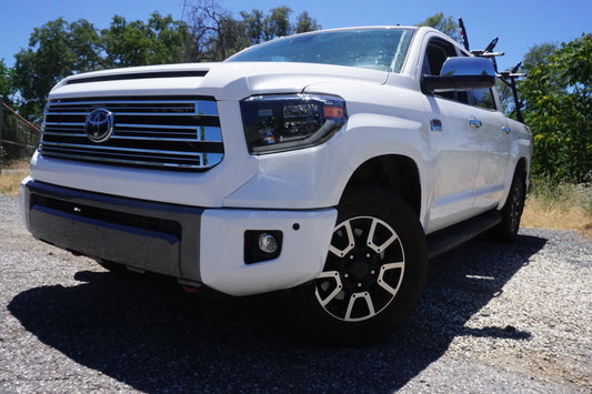 Up-close shot of a 2014-2021 Toyota Tundra with Super White BumperShellz on the front bumper, featuring sensor holes for the 2.5 generation Tundra, captured during the day