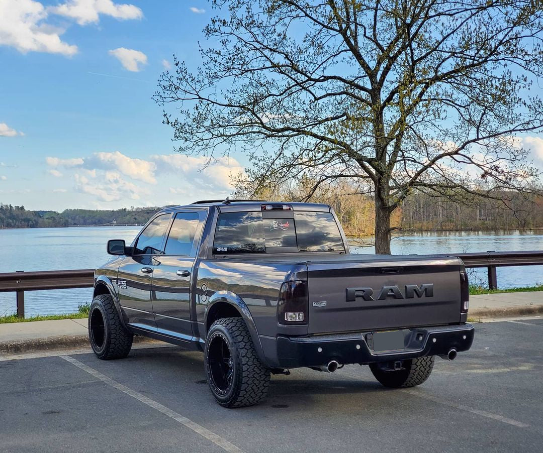 Dual Exhaust rear bumper covers installed on a RAM truck, parked outside of a lake