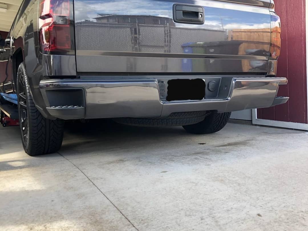 Gloss Black rear bumper covers installed on a 2014-2018 Chevy Silverado parked in a garage, showing off a fresh chrome delete look